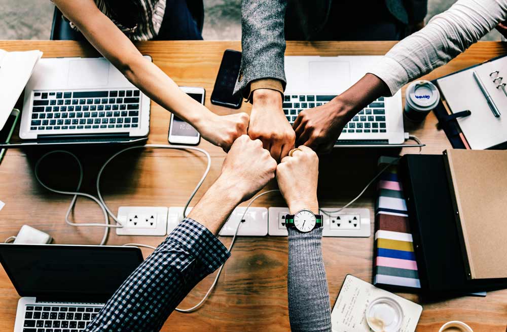 team fist bumping over the work table