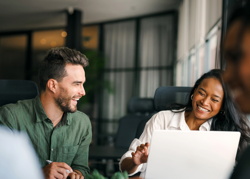 two professionals chatting in front of work table with laptops